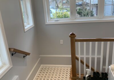 A tidy entryway with a patterned floor, staircase, and a window providing natural light.