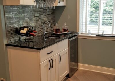 Modern kitchen corner with white cabinets and a gray backsplash.