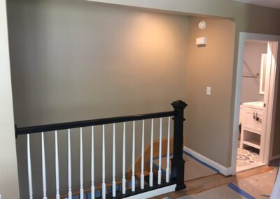 An interior view of a house showing a staircase banister and a partially visible bathroom in the background.