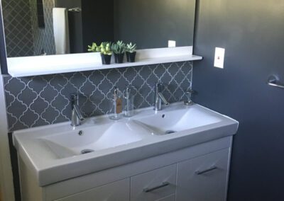 Modern bathroom with a double sink vanity and dark blue walls.