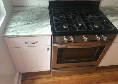 Stainless steel gas stove with a marble countertop in a modern kitchen.