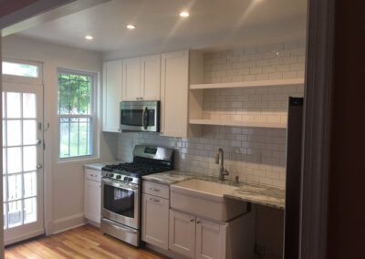 Modern kitchen with stainless steel appliances, white cabinetry, and subway tile backsplash.