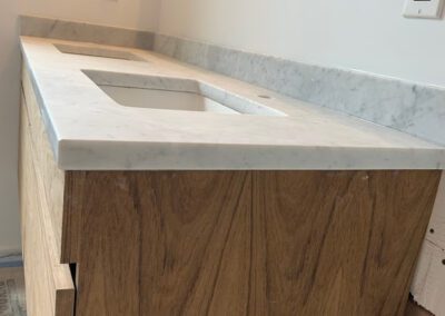 Modern bathroom vanity with a marble countertop and wooden cabinets.