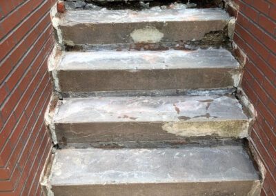 Worn-out concrete staircase with visible signs of deterioration and patches.