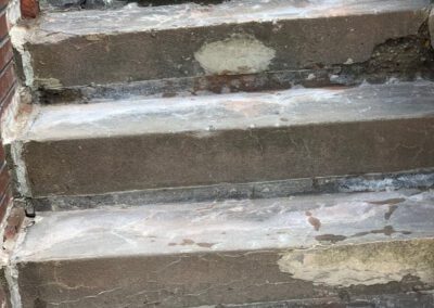 Worn brick staircase with chipped steps and missing mortar.