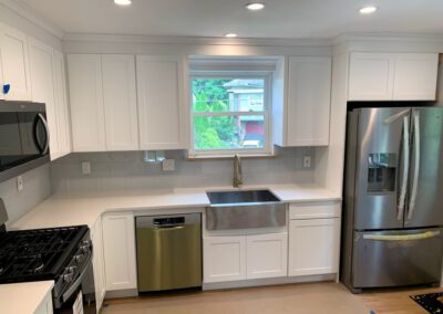 Modern kitchen interior with white cabinetry, stainless steel appliances, and a window above the sink.