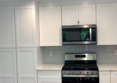 Modern kitchen with stainless steel appliances and white cabinetry.