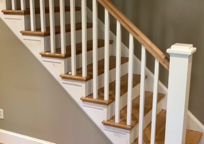 A wooden staircase with white balusters and handrail.