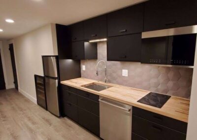 Modern kitchen with black cabinets, stainless steel appliances, and wooden countertops.