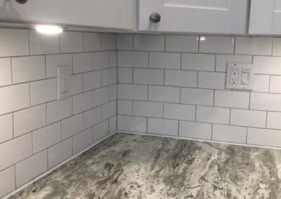 White subway tiles on kitchen backsplash with marble countertop.